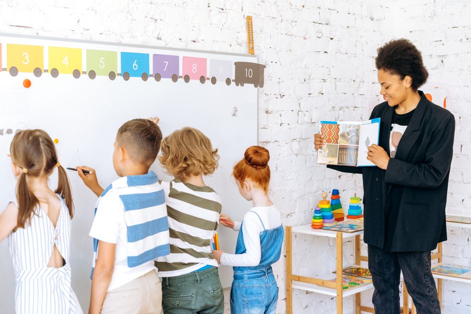 Children actively participating in classroom learning with a teacher guiding them.